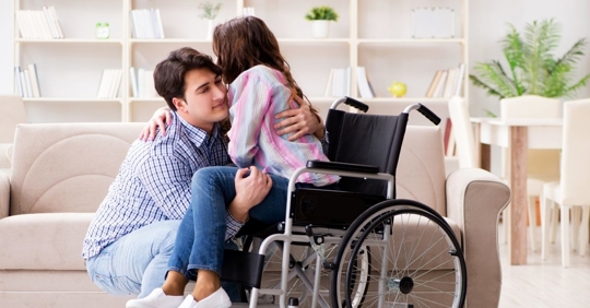 man helping young woman out of a wheelchair