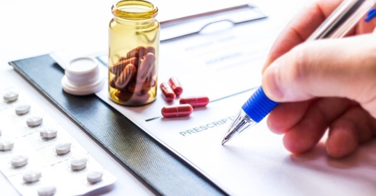 person writing on a note pad labeled "prescription"