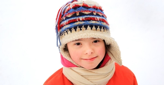 headshot of a child with Down syndrome wearing winter attire