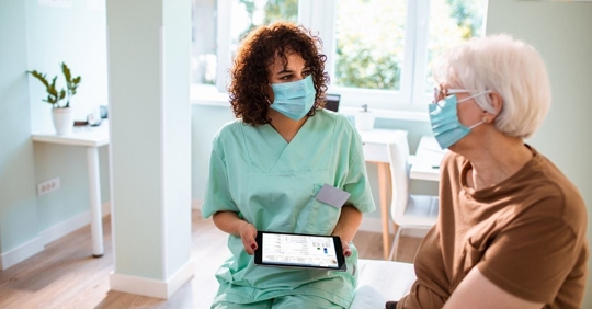 a nurse and older woman talking in a doctor's office