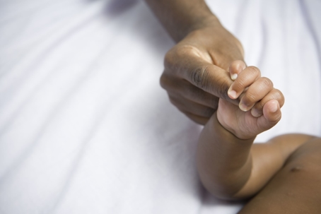 newborn baby holding mom's finger