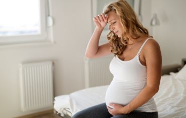 Pregnant woman sitting on edge of bed